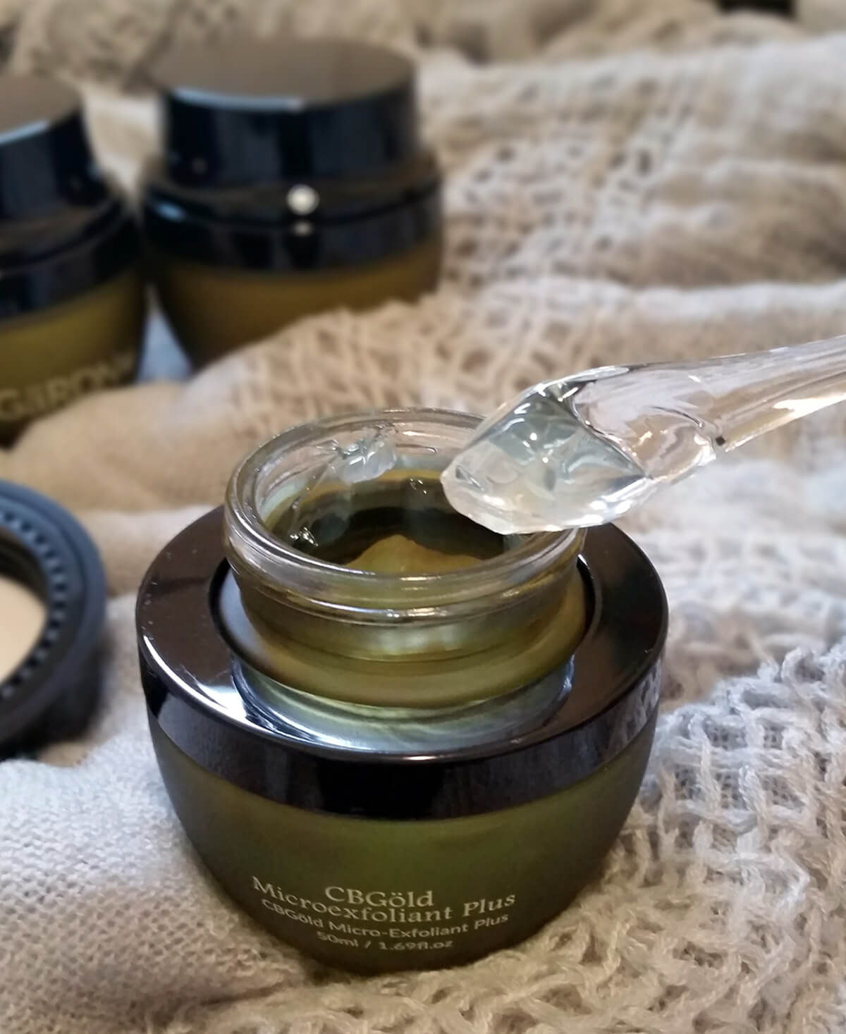 CBGold Exfoliant in jar with applicator lifting product out
