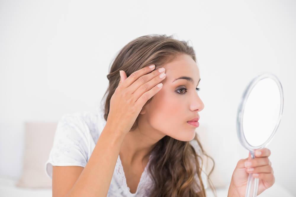 Woman looking at forehead in mirror