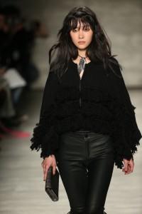 Model walks runway in fringe coat