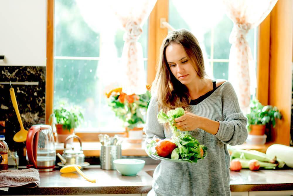 woman prepping green salad vegetables