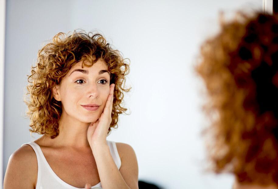 woman checking skin in mirror