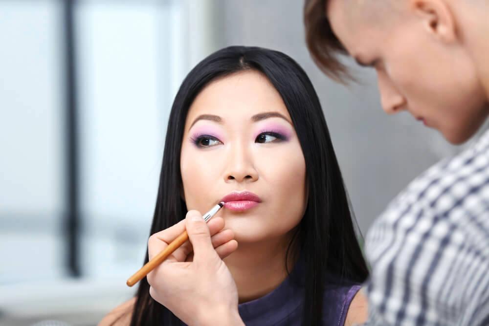 Makeup artist applying lipstick on woman