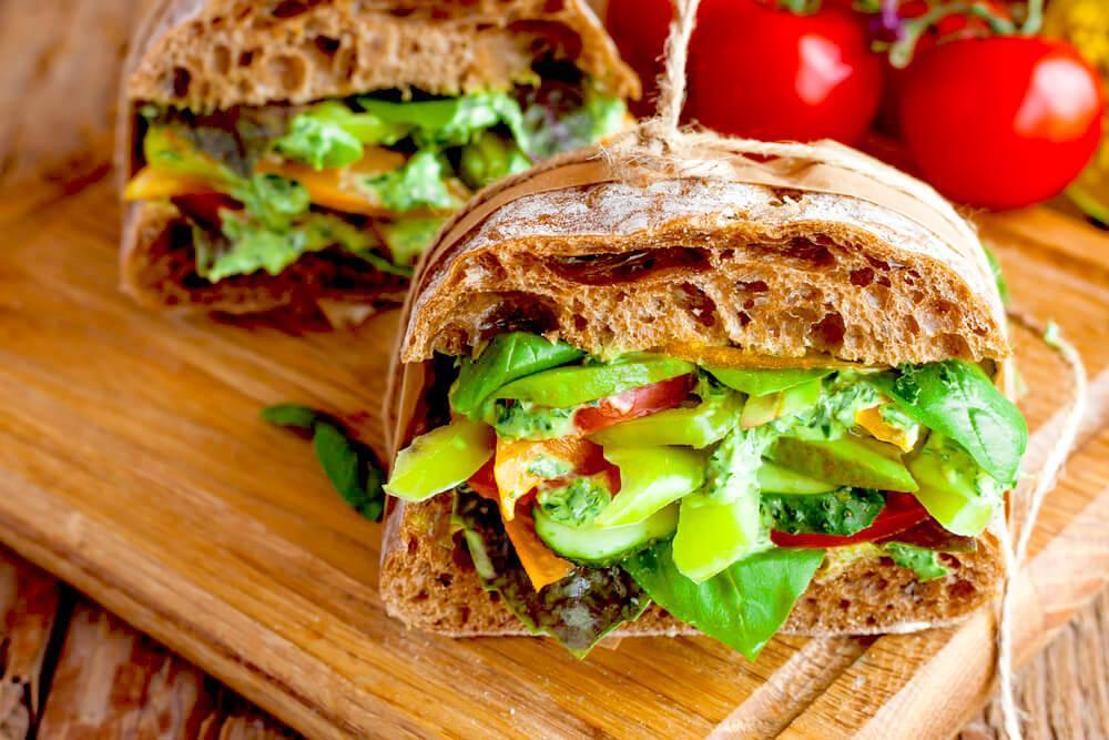 Thick veggie sandwich with multigrain bread, on rustic chopping board