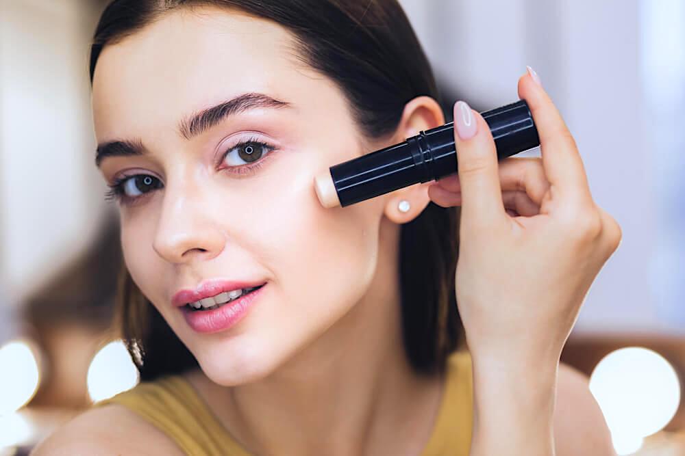 Woman using concealer stick