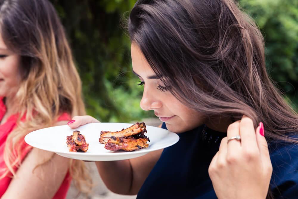 Woman sniffing beef ribs on her plate