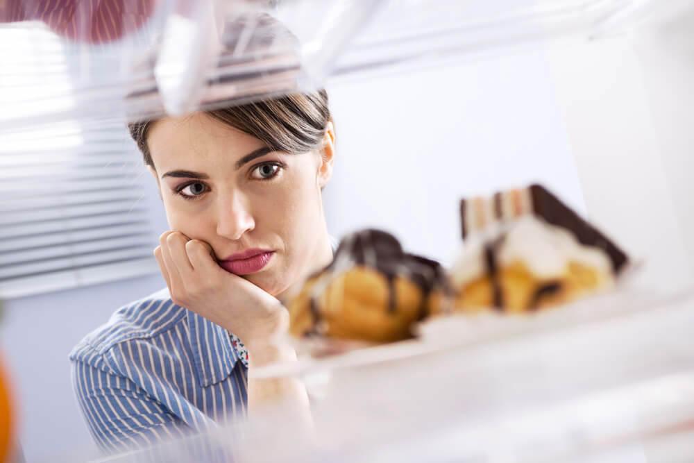 Woman looking longingly at donuts in the fridge
