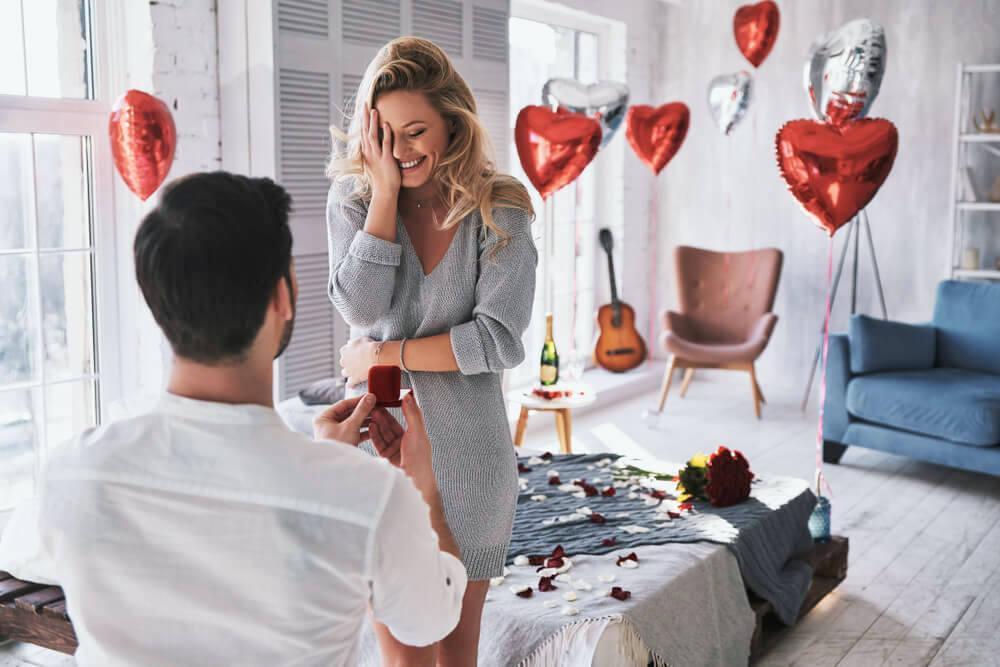 Man proposing to girlfriend in room, with heart-shaped balloons