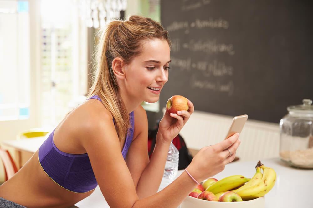 Athletic woman eating an apple in the kitchen