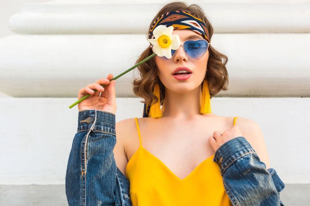 Fashionable woman in yellow dress and denim jacket, with a flower