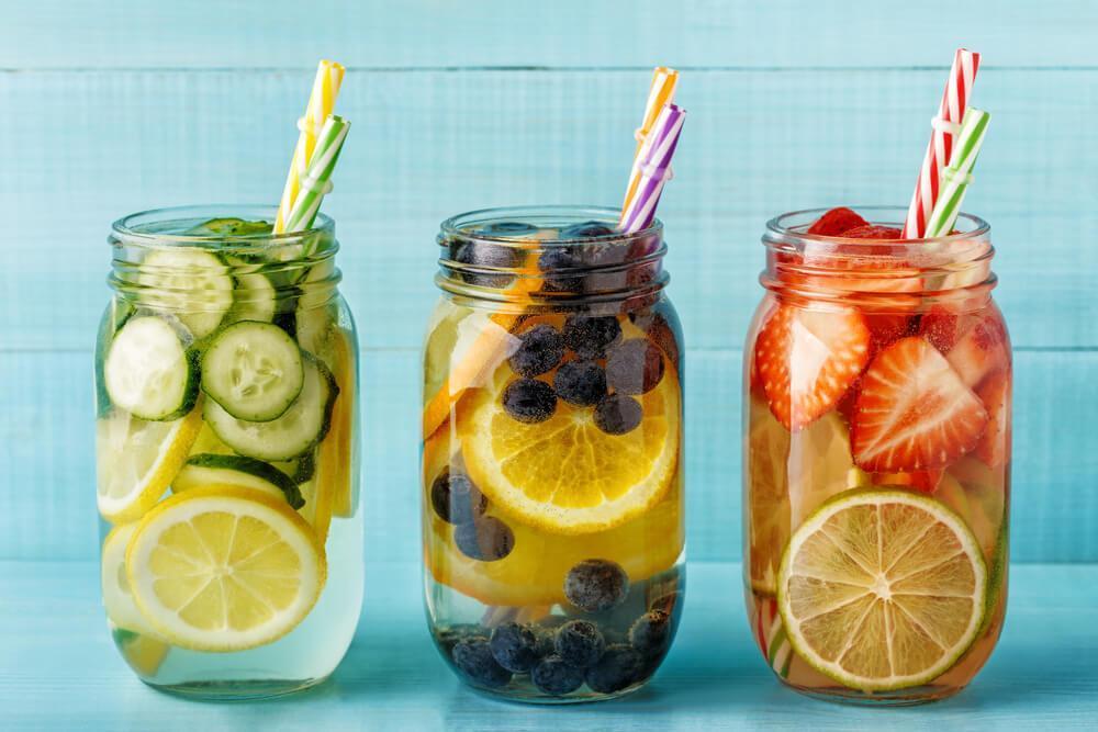 Three mason jars with fruit infused water and straws