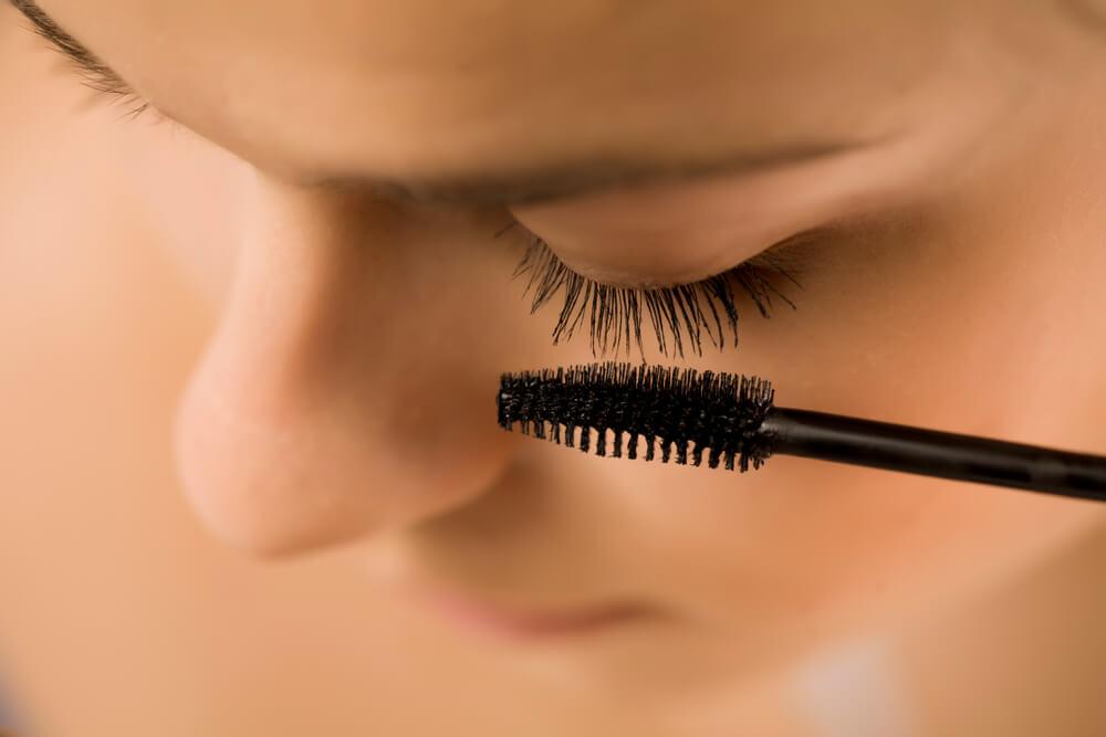 Woman brushing eyelashes with spoolie brush