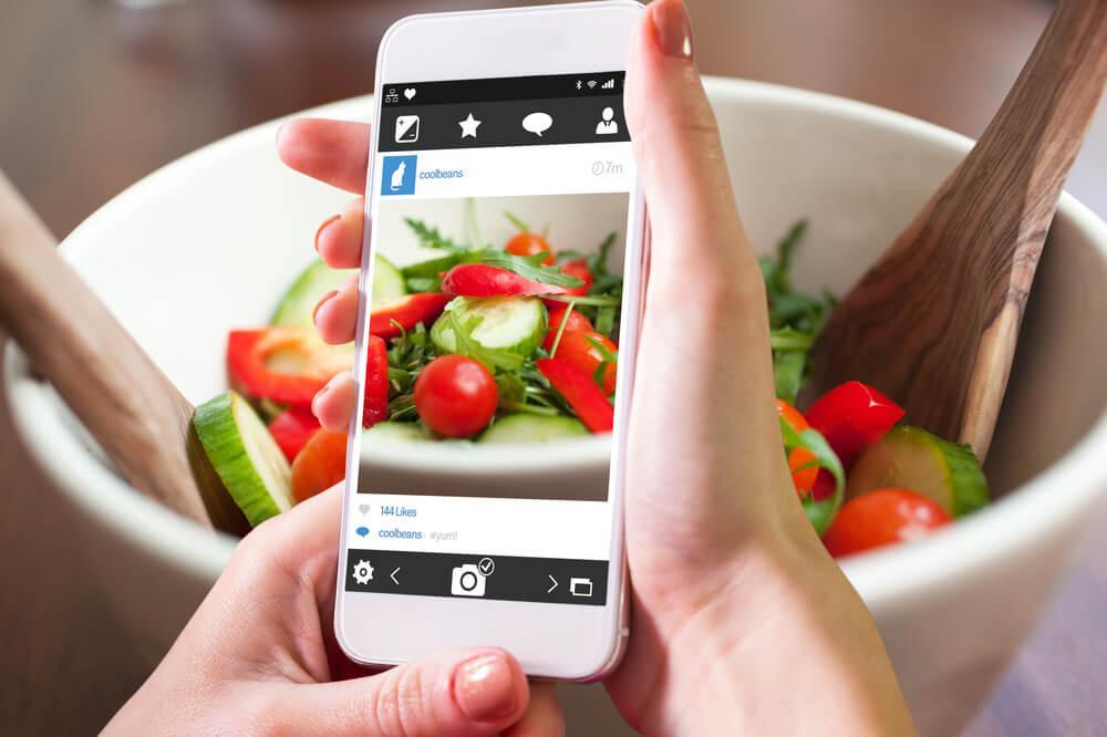 Woman holding phone while cooking