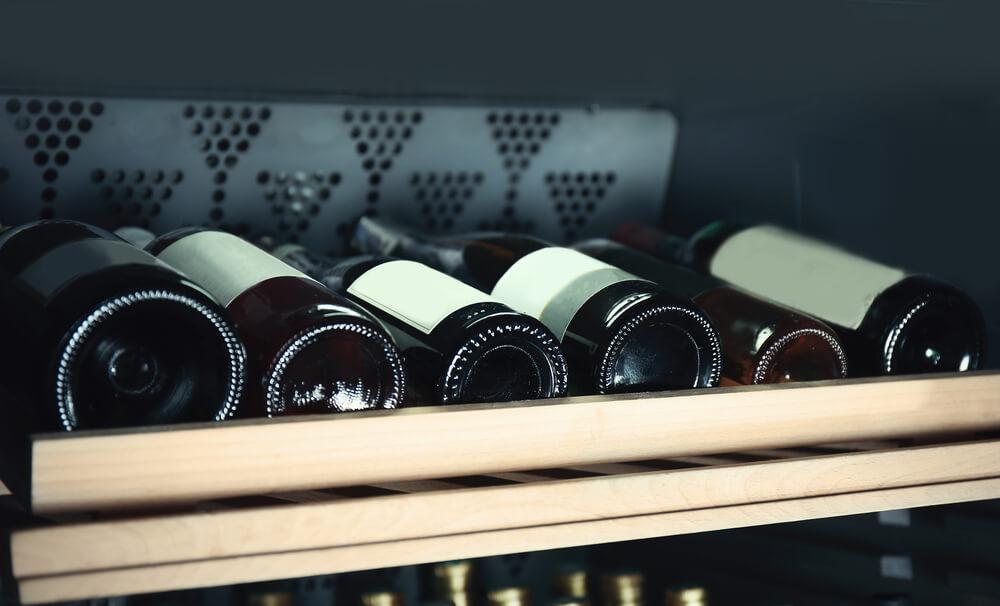 A fridge shelf with bottles of wine