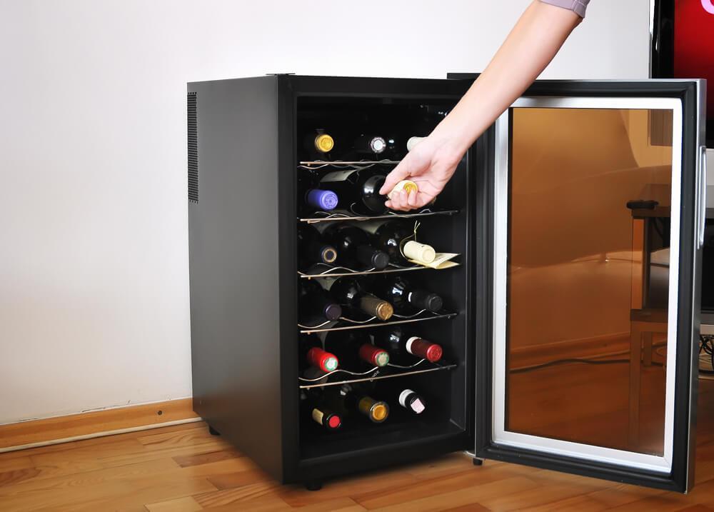 Someone taking a bottle of wine from a wine fridge