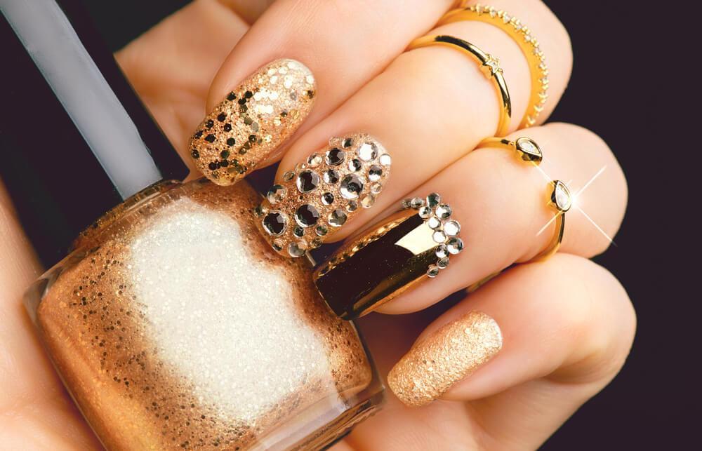 Bejeweled nails holding nail polish bottle