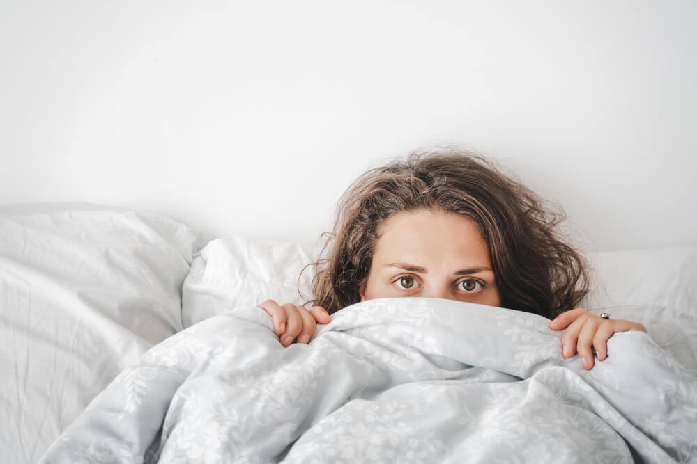 Woman hiding under blanket