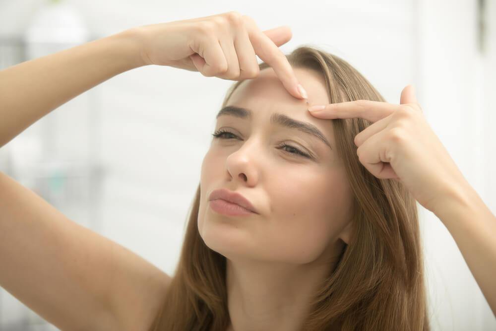 Woman squeezing spot on forehead