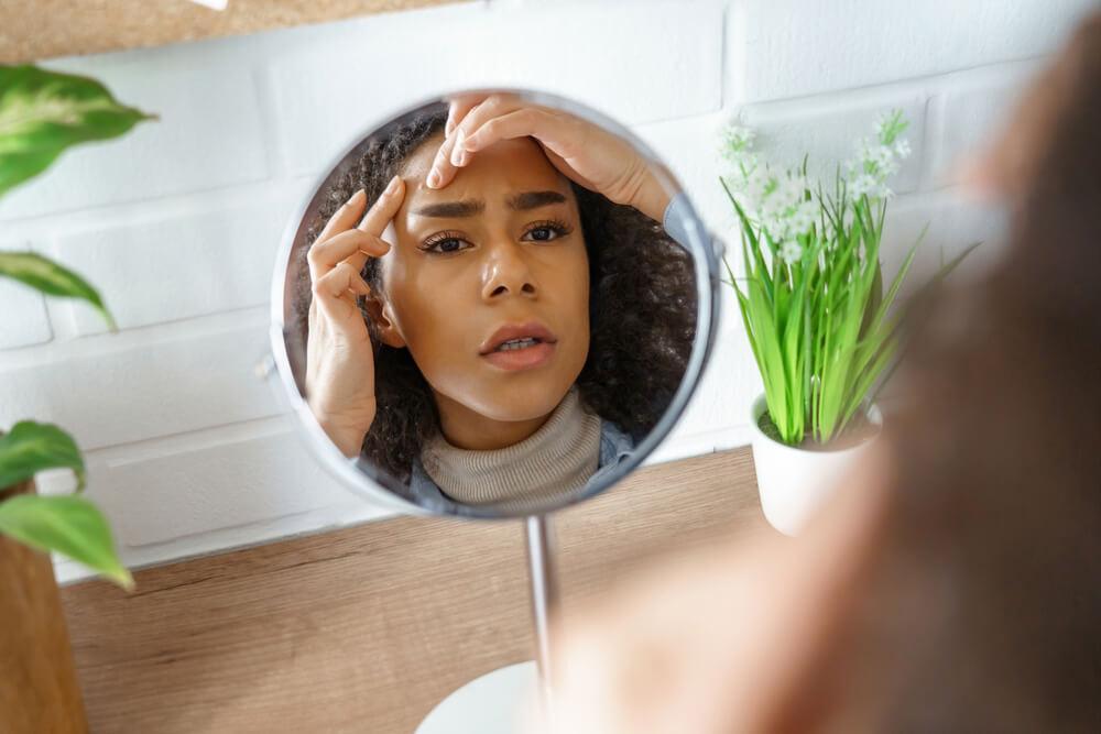 Woman looking at forehead in mirror